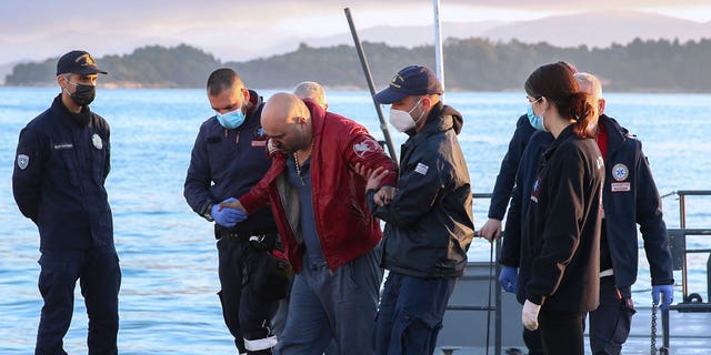 A slightly injured man helped by coast guard officers, arrives at the port of Corfu island, northwestern Greece, after the evacuation of a ferry, Friday, Feb. 18, 2022. 