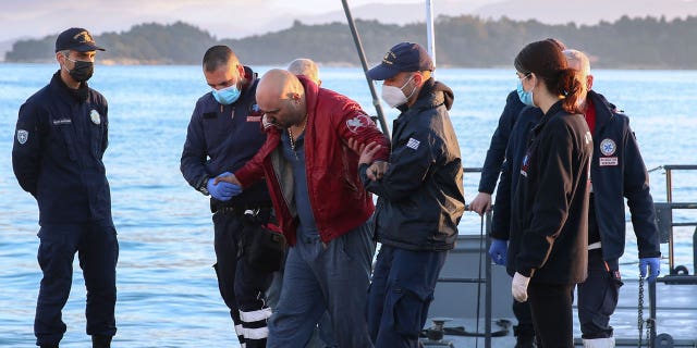 A slightly injured man helped by coast guard officers, arrives at the port of Corfu island, northwestern Greece, after the evacuation of a ferry, Friday, Feb. 18, 2022.