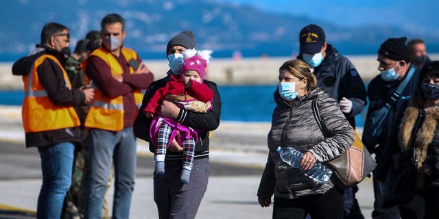 Passengers arrive at the port of Corfu island, northwestern Greece, after being evacuated from a ferry, Friday, Feb. 18, 2022. More than 280 people have been evacuated from a ferry in northwestern Greece that caught fire overnight while heading to southern Italy, authorities said.