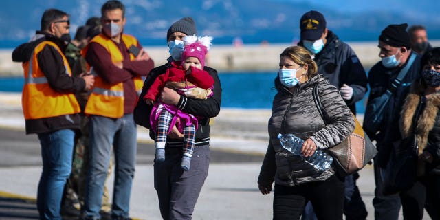 Passengers arrive at the port of Corfu island, northwestern Greece, after being evacuated from a ferry, Friday, Feb. 18, 2022. More than 280 people have been evacuated from a ferry in northwestern Greece that caught fire overnight while heading to southern Italy, authorities said.