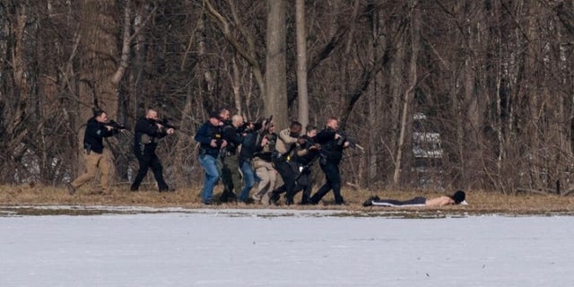 Police approach a suspect on the south bank of the North River in Bridgewater, Va. following a shooting at Bridgewater College Tuesday, Feb. 1, 2022. 