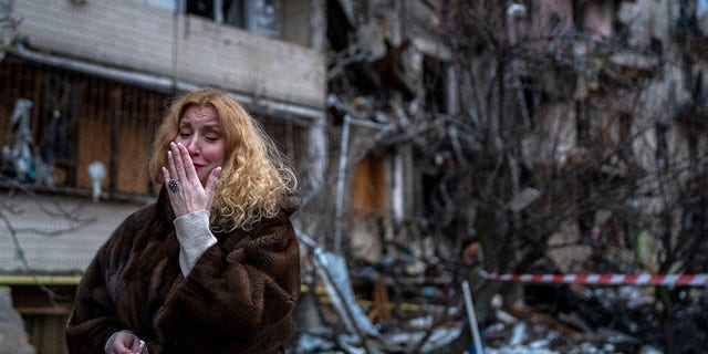 Natali Sevriukova reacts next to her house following a rocket attack the city of Kyiv, Ukraine, Friday, Feb. 25, 2022. 