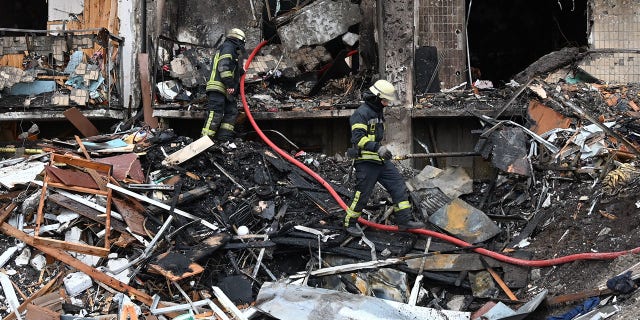 Firefighters work at a damaged residential building at Koshytsa Street, a suburb of the Ukrainian capital Kyiv, where a military shell allegedly hit, on Feb. 25, 2022.