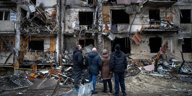 People look at the damage following a rocket attack in Kyiv, Ukraine, Friday, Feb. 25, 2022. 