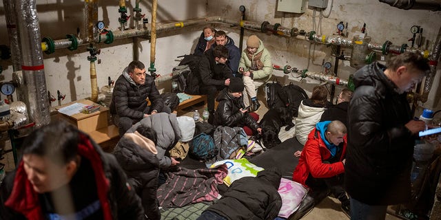 People take shelter at a building basement while sirens sound, announcing new attacks in the city of Kyiv, Ukraine, Friday, Feb. 25, 2022. 