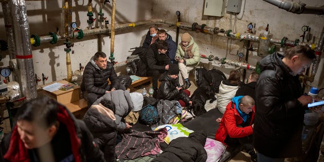 People take shelter at a building basement while the sirens sound announcing new attacks in the city of Kyiv, Ukraine, Friday, Feb. 25, 2022.