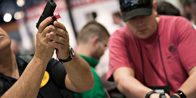 Attendees look over Glock, Inc. pistols on the exhibition floor of the 144th National Rifle Association (NRA) Annual Meetings and Exhibits at the Music City Center in Nashville, Tennessee, April 11, 2015.