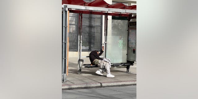 A homeless man sits at a San Francisco bus shelter in the Tenderloin District 