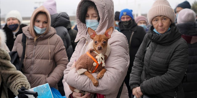 A woman holds her dog as she waits with others to cross from Ukrainian government controlled areas to pro-Russian separatists' controlled territory in Stanytsia Luhanska, the only crossing point open daily, in the Luhansk region, eastern Ukraine, Tuesday, Feb. 22, 2022. (WHD Photo/Vadim Ghirda)