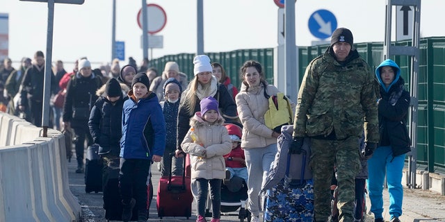A Polish border guard assists refugees from Ukraine as they arrive to Poland at the Korczowa border crossing, Poland, Saturday, Feb. 26.