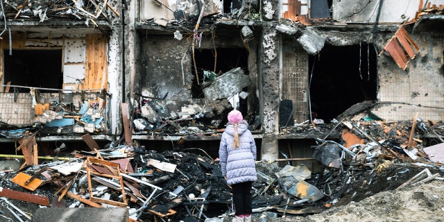 On Feb. 25, 2022 in Kyiv, Ukraine, a girl looks at the crater left by an explosion in front of an apartment building, which was heavily damaged during ongoing military operations.