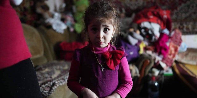 On Feb. 20, 2022, this young girl — age 4 — is photographed inside a house where she lives with her family after shelling by separatist forces in Novognativka, in eastern Ukraine.
