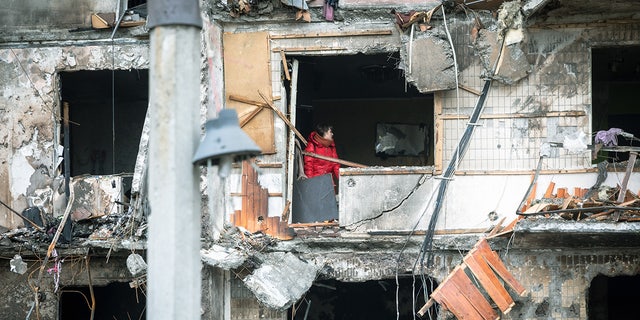 On Feb. 25, 2022, in Kyiv, Ukraine, a woman works to clear debris in her apartment after the building was heavily damaged in military operations.