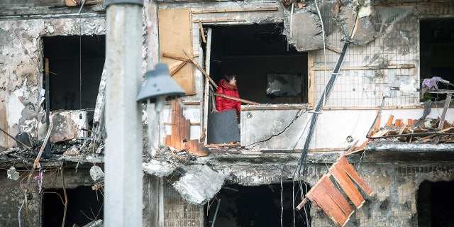 On Feb. 25, 2022, in Kyiv, Ukraine, a woman works to clear debris in her apartment after the building was heavily damaged in military operations.