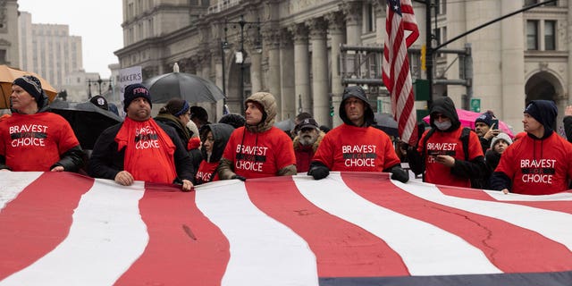 People carry a large American flag during the anti-vaccine mandate protest ahead of possible termination of New York City employees due to their vaccination status, Monday, Feb. 7, 2022, in New York. 