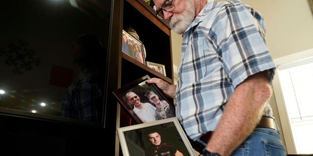 Joey Reed holds photos of son Trevor Reed, a Marine veteran and Russian prisoner, at his home in Fort Worth, Texas, Feb. 15, 2022. Russia is holding Trevor Reed, who was sentenced to nine years on charges he assaulted a police officer.