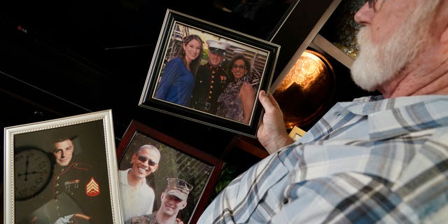 Joey Reed holds photos of son Trevor Reed, a Marine veteran and Russian prisoner, at his home in Fort Worth, Texas, Feb. 15, 2022. Russia is holding Trevor Reed, who was sentenced to nine years on charges he assaulted a police officer. 