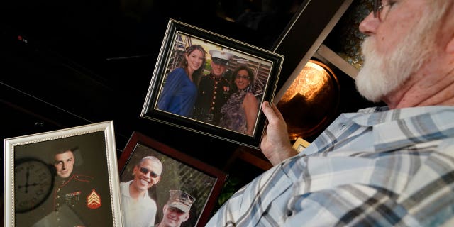 Joey Reed holds photos of son Trevor Reed, a Marine veteran and Russian prisoner, at his home in Fort Worth, Texas, Feb. 15, 2022. Russia is holding Trevor Reed, who was sentenced to nine years on charges he assaulted a police officer.