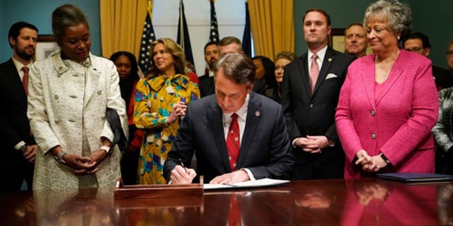 Virginia Gov. Glenn Youngkin, center, signs executive orders in the Governors conference room at the Capitol on Saturday Jan. 15, 2022, in Richmond, Va.