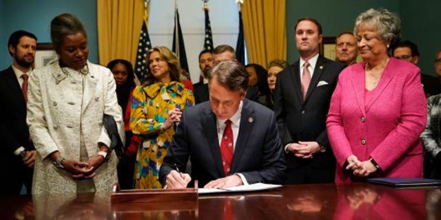 Virginia Gov. Glenn Youngkin, center, signs executive orders in the Governors conference room at the Capitol on Saturday Jan. 15, 2022, in Richmond, Va.