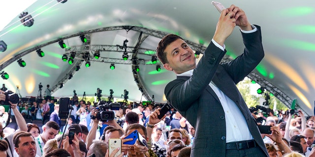 Ukrainian President Volodymyr Zelenskyy takes a selfie at the first congress of his party called Servant of the People in the city Botanical Garden, Kiev, Ukraine, Sunday, June 9, 2019.