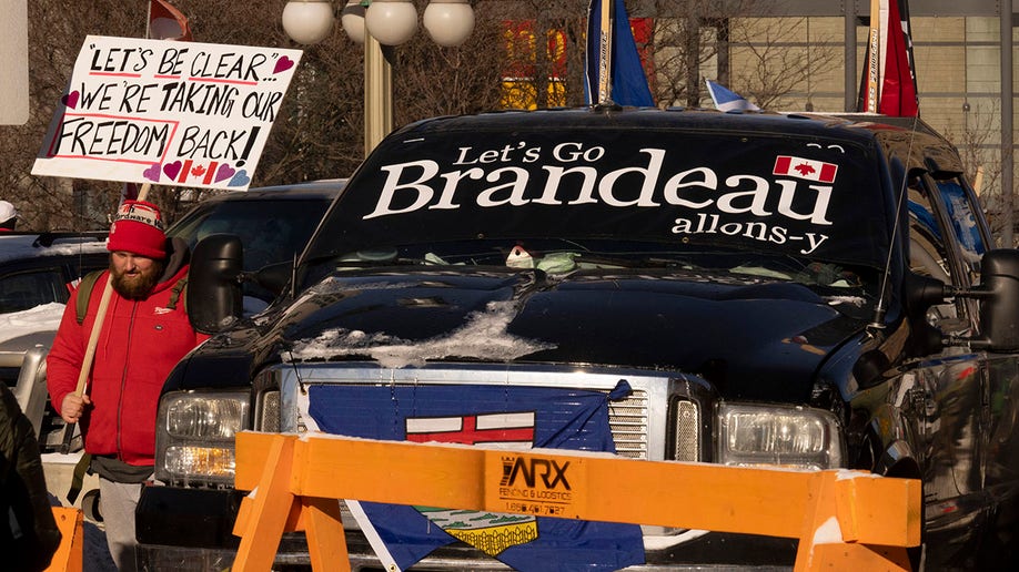 A protester walks past a truck parked in the street in the downtown core during a demonstration against COVID-19 restrictions, Saturday, Feb. 5, 2022, in Ottawa, Ontario. 