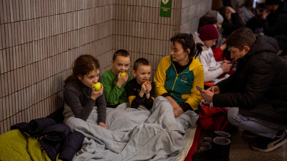 A family sit in the Kyiv subway, using it as a bomb shelter in Kyiv, Ukraine, Friday, Feb. 25, 2022. In Ukraine's capital, many residents hurried underground for safety overnight Thursday and Friday as Russian forces fired on the city and moved closer. (AP Photo/Emilio Morenatti)