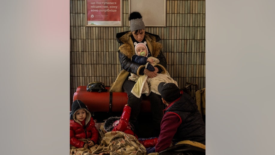 A family sit in the Kyiv subway, using it as a bomb shelter in Kyiv, Ukraine, Friday, Feb. 25, 2022. In Ukraine's capital, many residents hurried underground for safety overnight Thursday and Friday as Russian forces fired on the city and moved closer. (AP Photo/Emilio Morenatti)