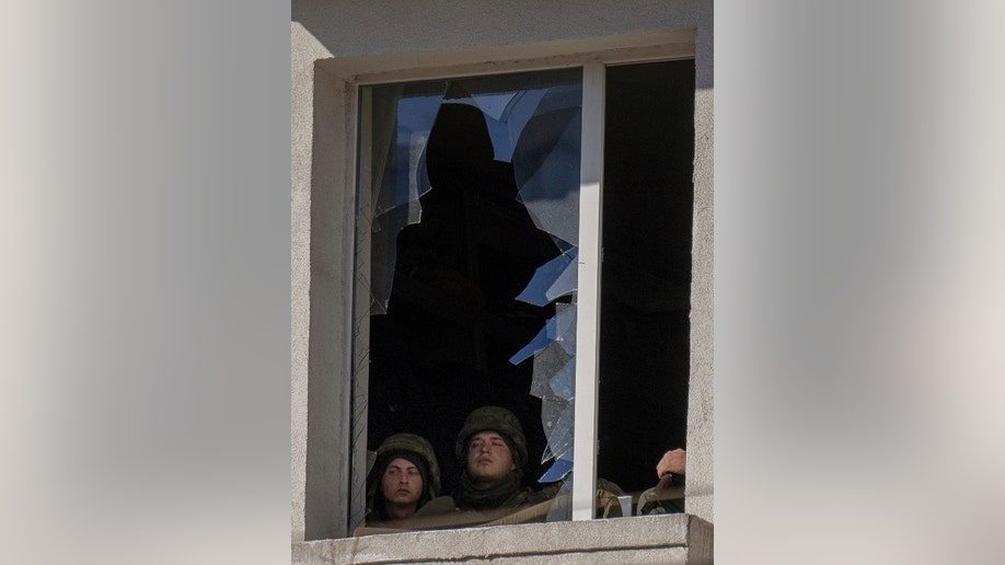 Ukrainian soldiers look out from a broken window inside a military facility, after an explosion in Kyiv, Ukraine, Saturday, Feb. 26, 2022. Russian troops stormed toward Ukraine's capital Saturday, and street fighting broke out as city officials urged residents to take shelter. (AP Photo/Emilio Morenatti)