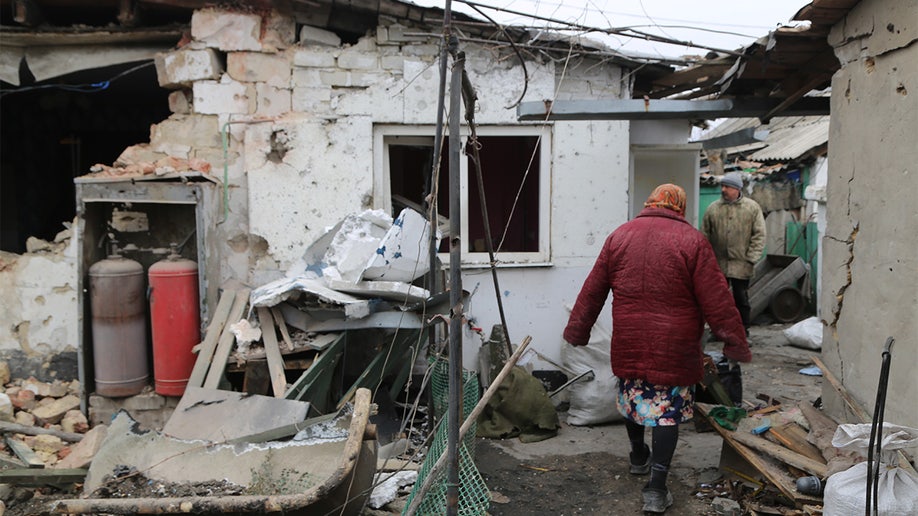 A woman is seen in front of a damaged building in Donetsk's Petrovskaya