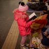 A girl looks at a notebook next to her mother as they stand in the Kyiv subway, using it as a bomb shelter, in Ukraine, Saturday Feb. 26, 2022.