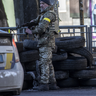 A Ukrainian soldier stands guard behind tires in Zhuliany neighborhood of Kyiv during Russia's invasion of Ukraine, on February 26, 2022. 