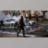 Ukrainian soldiers take positions outside a military facility as two cars burn, in a street in Kyiv, Ukraine, Saturday, Feb. 26, 2022. Russian troops stormed toward Ukraine's capital Saturday, and street fighting broke out as city officials urged residents to take shelter.