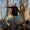 People stand next to fragments of military equipment on the street in the aftermath of an apparent Russian strike in Kharkiv in Kharkiv, Ukraine, Thursday, Feb. 24, 2022.