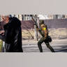 A Ukrainian soldier runs holding his weapon outside a military facility, in Kyiv, Ukraine, Saturday, Feb. 26, 2022. Russian troops stormed toward Ukraine's capital Saturday, and street fighting broke out as city officials urged residents to take shelter.