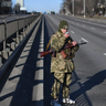 An Ukrainian service member drinks a cup of tea as he patrol the empty road on west side of the Ukrainian capital of Kyiv in the morning of February 26, 2022