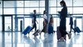 People traveling by plane during COVID 19, wearing N95 face masks, carrying luggage in airport terminal. (iStock)