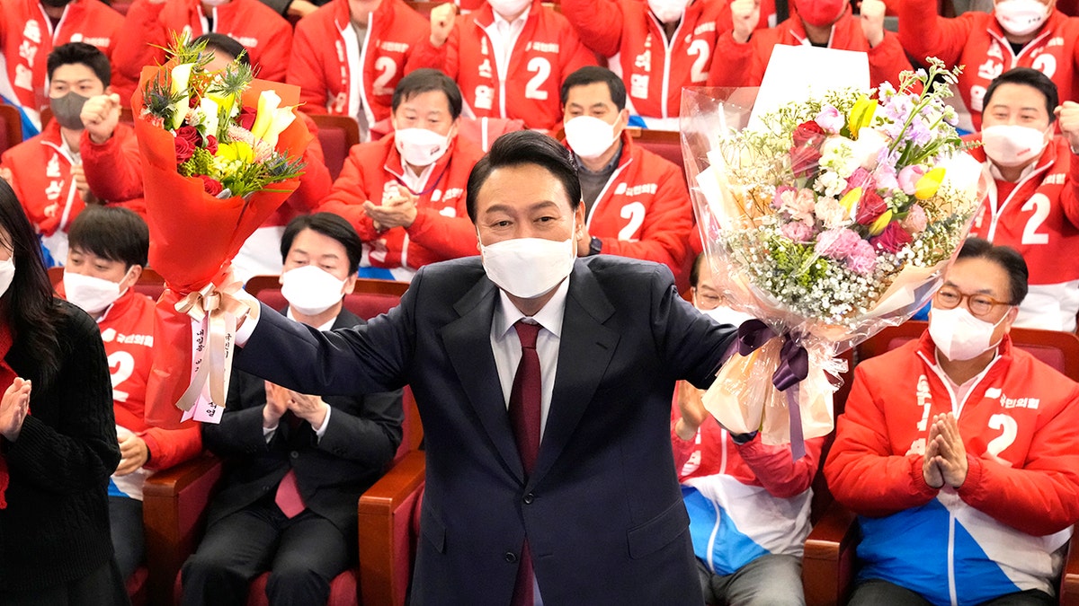 Yoon Suk Yeol, the presidential candidate of the main opposition People Power Party, who was elected South Korea's new president on Thursday, holds bouquets as he is congratulated by party's members and lawmakers at the National Assembly in Seoul, South Korea, Thursday, March 10, 2022. 