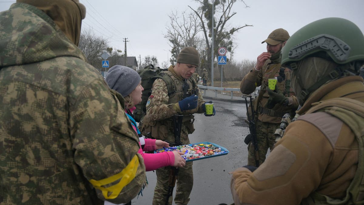 A woman offers sweets to Ukrainian servicemen in the village of Yasnohorodka