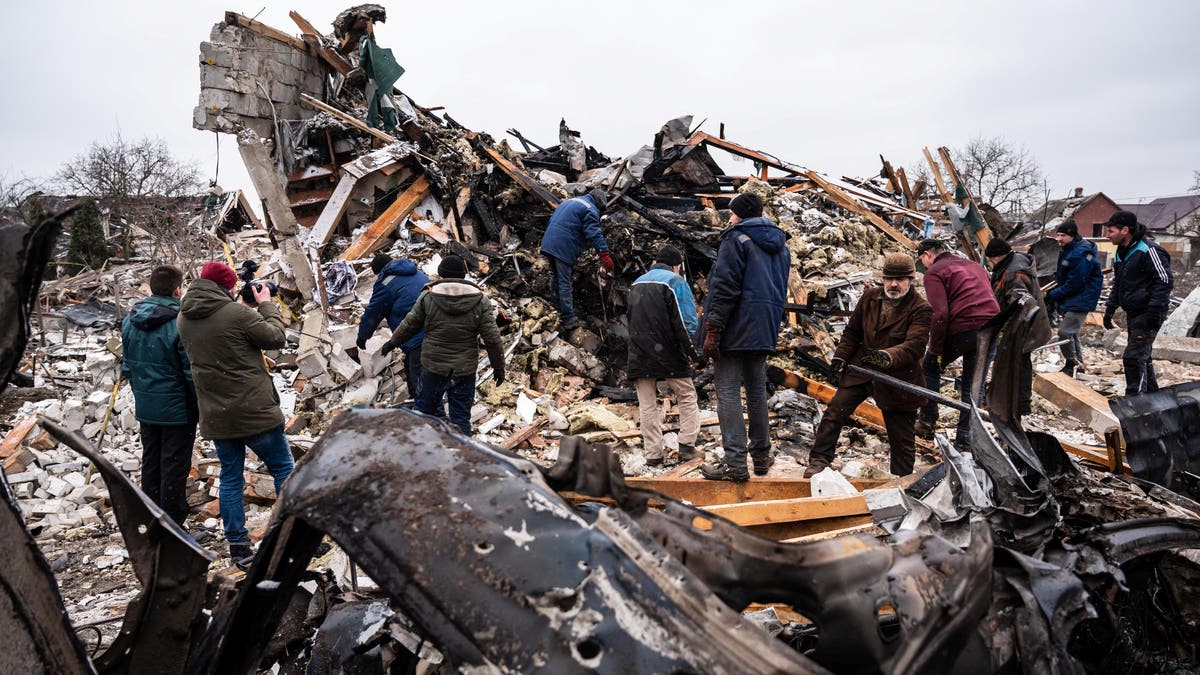 Local residents work among remains of a residential building destroyed by shelling, as Russia's invasion of Ukraine continues, in Zhytomyr