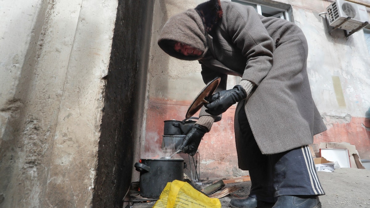 Local resident Antonina, 68, cooks soup in a street during Ukraine-Russia conflict in the besieged southern port city of Mariupol, Ukraine March 20, 2022. REUTERS/Alexander Ermochenko