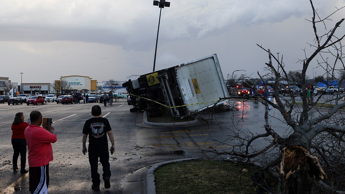 People look at an overturned truck in a parking lot after a tornado in a widespread storm system touched down in Round Rock, Texas, U.S., March 21, 2022.