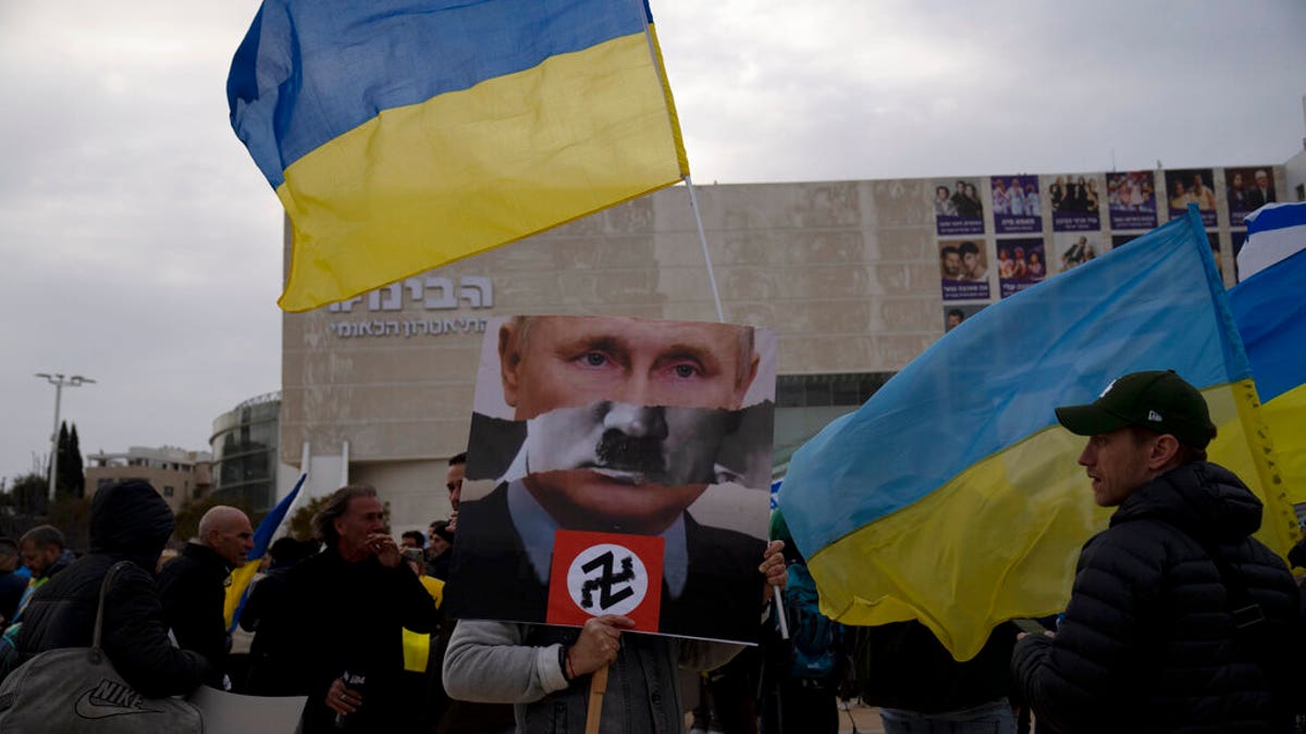 A protester in Habima Square holds a depiction of Russian President Vladimir Putin in Tel Aviv, Israel, as people gather to watch Ukrainian President Volodymyr Zelenskyy in a video address to the Knesset, Israel's parliament.