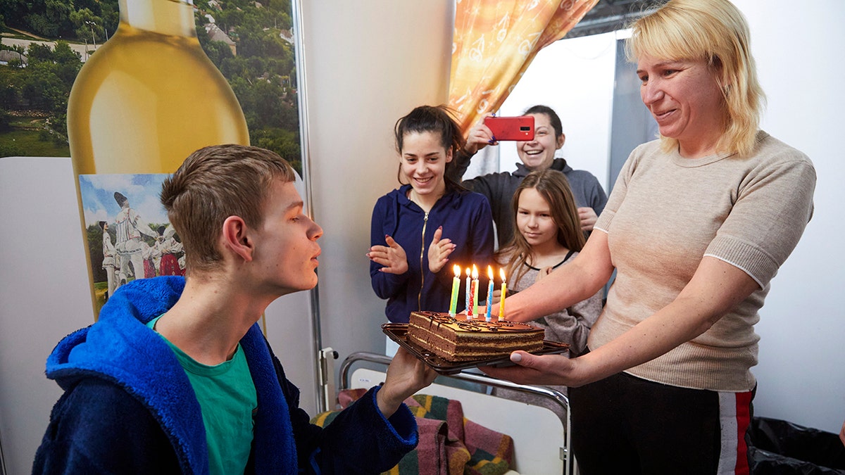 A Ukrainian young man blows the candles on a birthday cake at a facility for refugees in Chisinau, Moldova, Monday, Feb. 28, 2022.