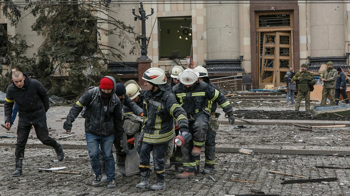 Ukrainian emergency service personnel carry a body of a victim out of the damaged City Hall building following shelling in Kharkiv, Ukraine, Tuesday, March 1, 2022.