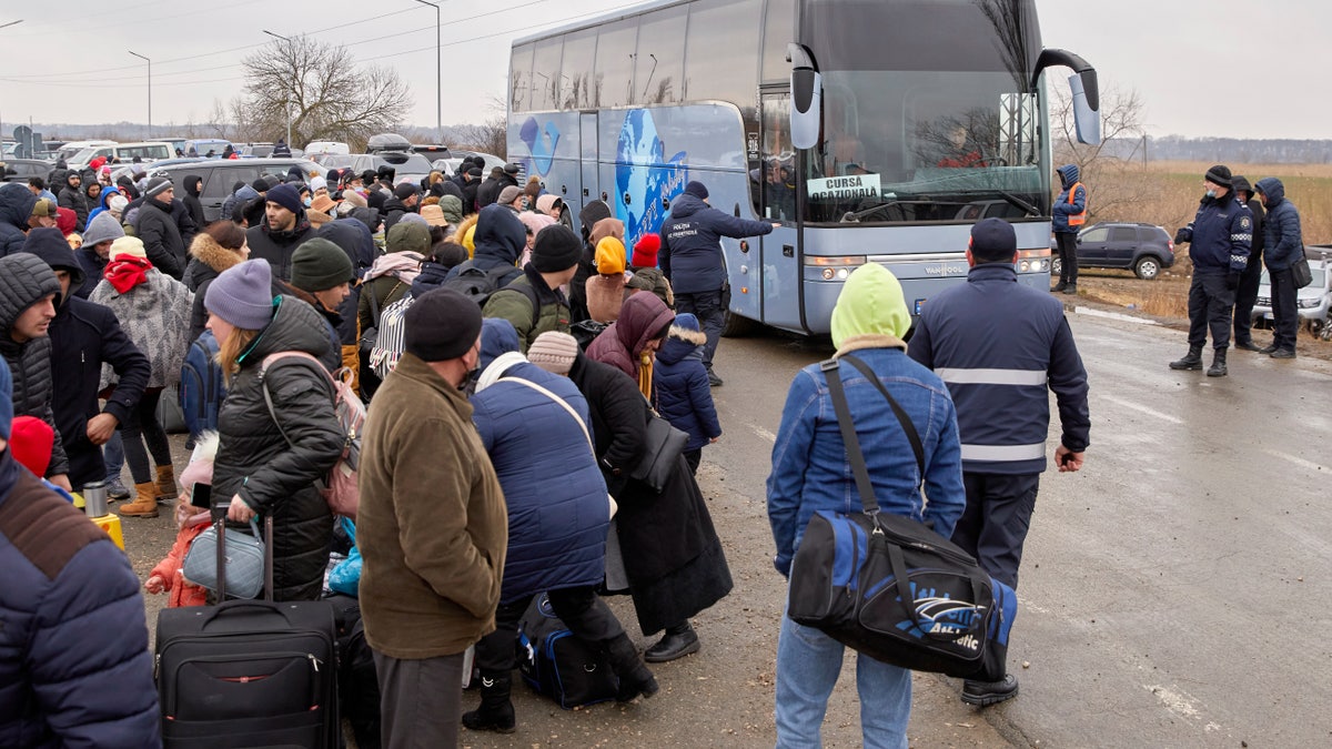 Refugees fleeing war in Ukraine wait to board a bus as they arrive to Palanca, Moldova, Tuesday, March 1, 2022.