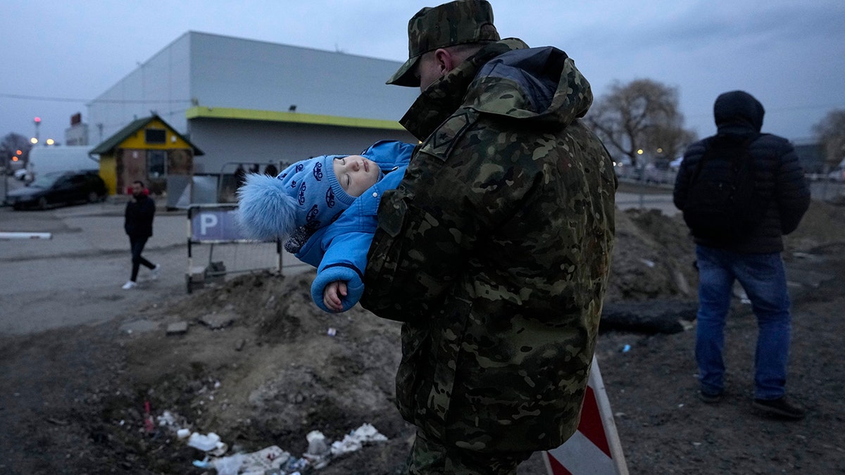 A Polish soldier carries a baby of a Ukrainian refugee upon their arrival at the border crossing in Medyka, southeastern Poland, Wednesday, March 2, 2022. 