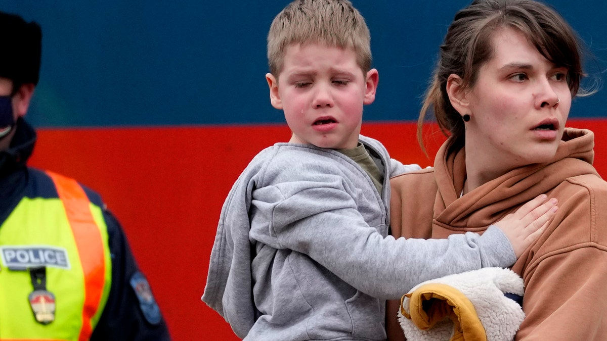 A woman carries a crying child as she arrives at the train station in Zahony, Hungary, on March 5, 2022. (AP Photo/Darko Vojinovic)
