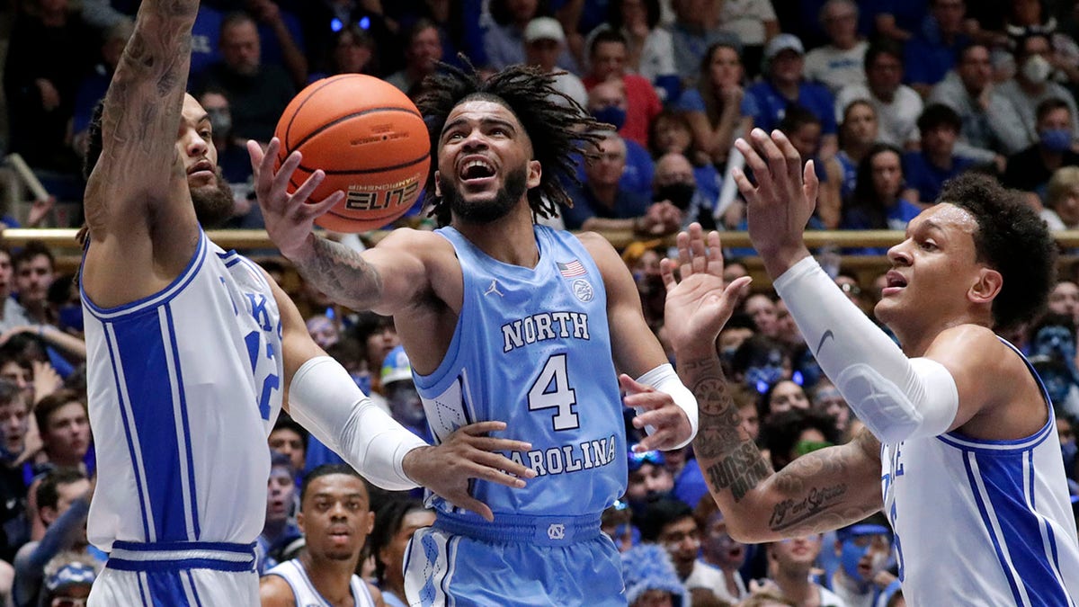 North Carolina guard R.J. Davis (4) drives between Duke forwards Theo John, left, and Paolo Banchero, right, during the first half of an NCAA college basketball game Saturday, March 5, 2022, in Durham, N.C.