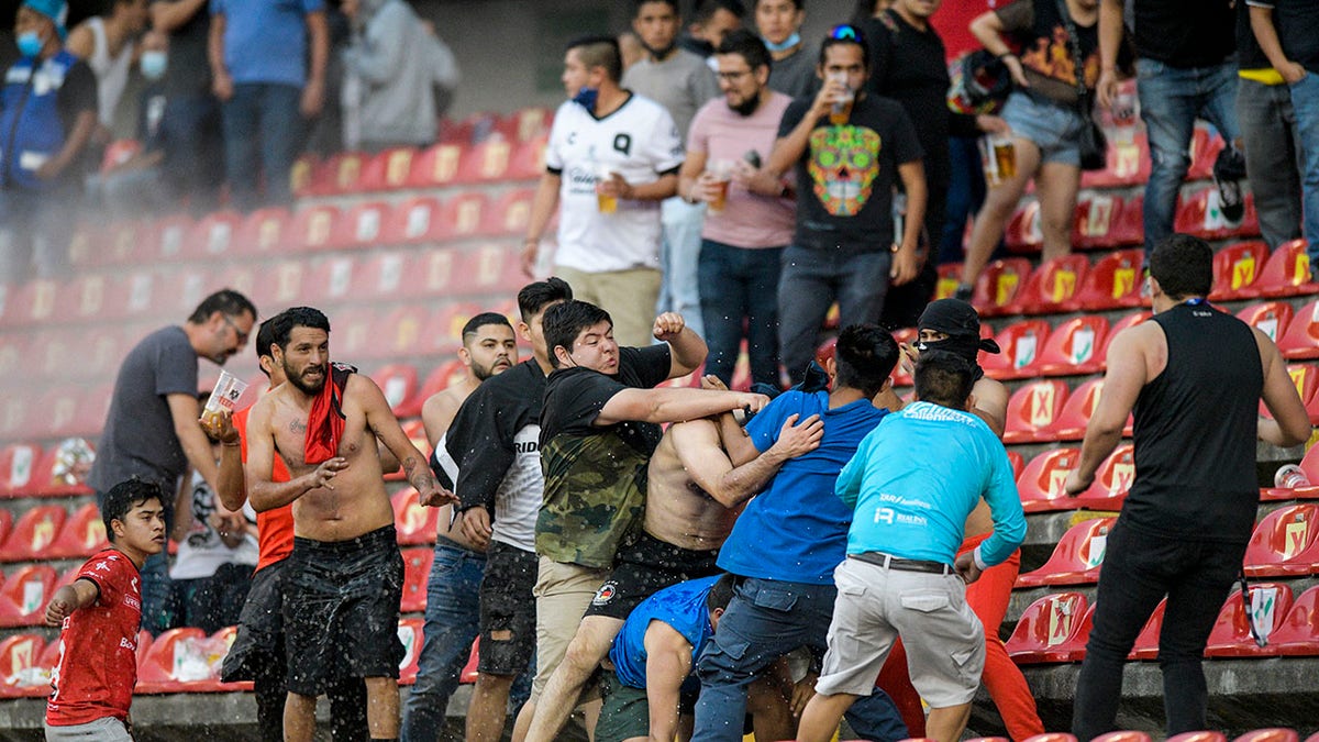 Fans clash during a Mexican soccer league match between the host Queretaro and Atlas from Guadalajara, at the Corregidora stadium, in Queretaro, Mexico, Saturday, March 5, 2022. Multiple people were injured in the brawl, including two critically.